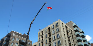 flag og kranse over skelettet til boligerne på Strandlodsvej - blå himmel